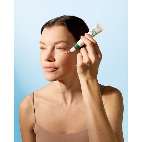 Woman applying skincare product to her face against a light blue background