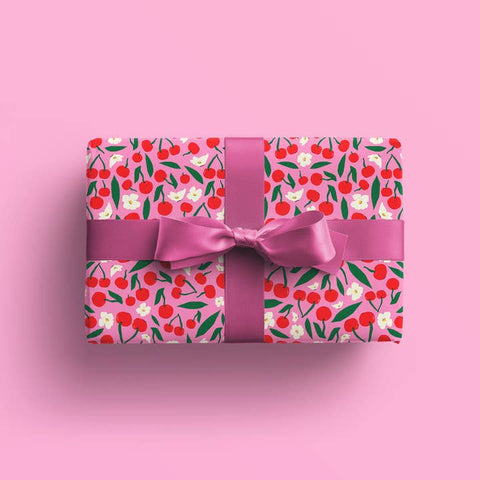 Gift box with cherry pattern and pink ribbon on a pink background