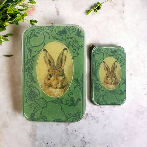 Two green tins with rabbit illustrations on a marble surface.
