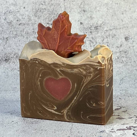 Bar of soap with a heart and leaf design on a textured surface