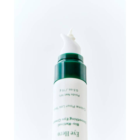 Skincare bottle with green cap and white label on a light gray background
