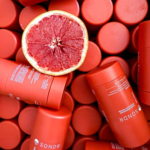 Red skincare product containers with a halved grapefruit on top