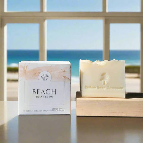 Beach-themed soap with packaging on a surface with a window view of the ocean.