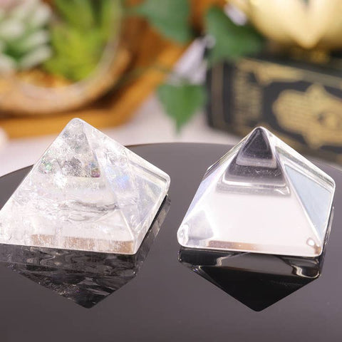 Two crystal pyramids on a reflective surface with a blurred background