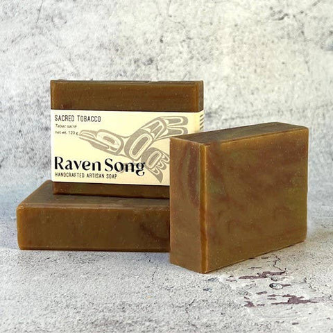 Two bars of brown soap with a 'Raven Song' label on a textured gray background