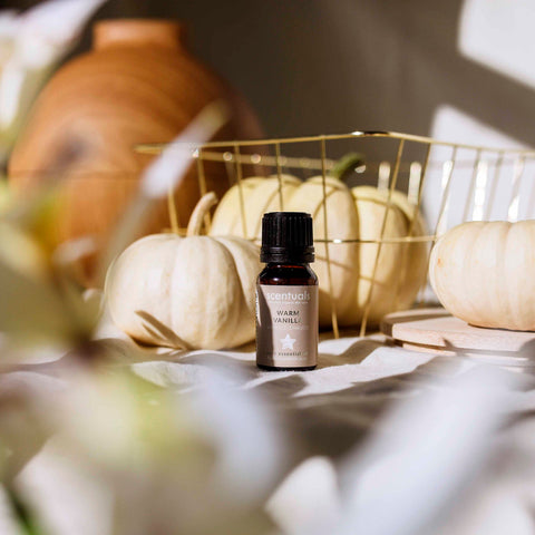 Bottle of Venturia Warm Vanilla essential oil with pumpkins and a basket in the background