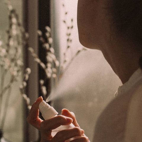 Person holding a white spray bottle with a blurred background