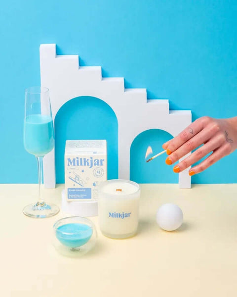 Milkjar product with a candle and glasses on a blue background