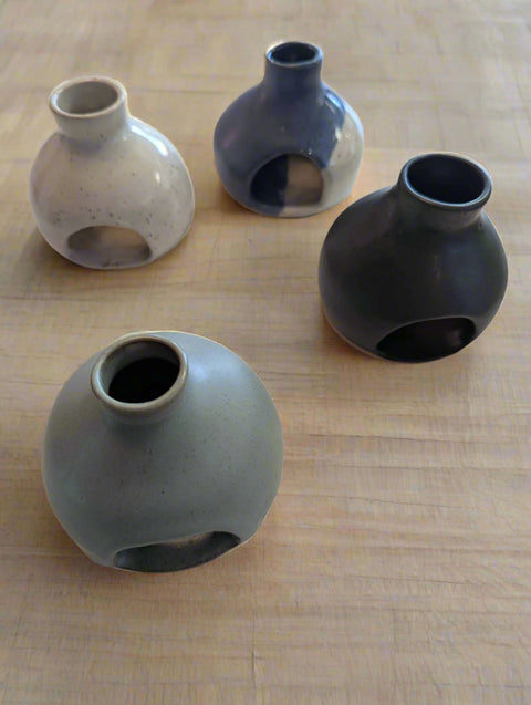 Four ceramic vases of different sizes and colors on a white surface