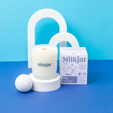 Milkjar candle and packaging on a blue background