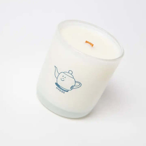 Candle with a cartoon teapot design on a white background