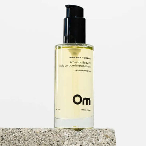 Glass bottle of Om Organics body oil with wild plum scent