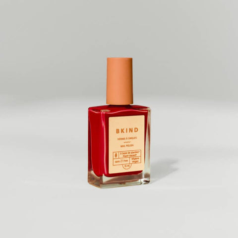 Red nail polish bottle with a brown cap on a light gray background