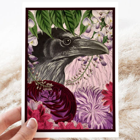 Framed artwork of a crow surrounded by flowers and leaves on a textured surface.