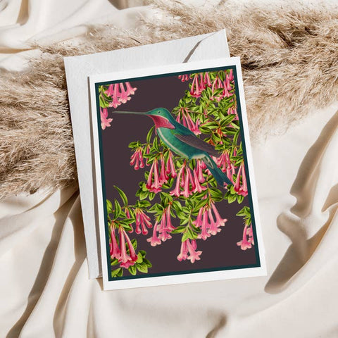 Greeting card with a hummingbird and pink flowers design on a textured surface
