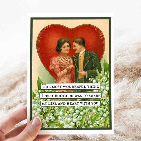Vintage-style card with a couple and romantic quote, held by a hand on a textured surface.