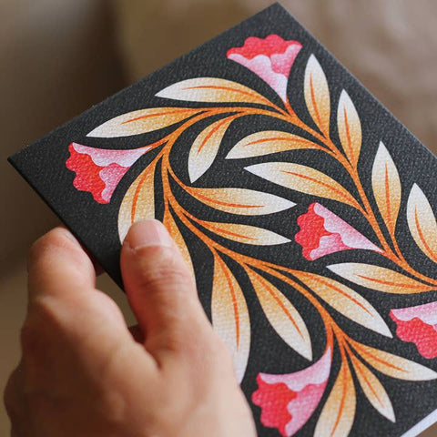 Hand holding a black card with colorful floral design