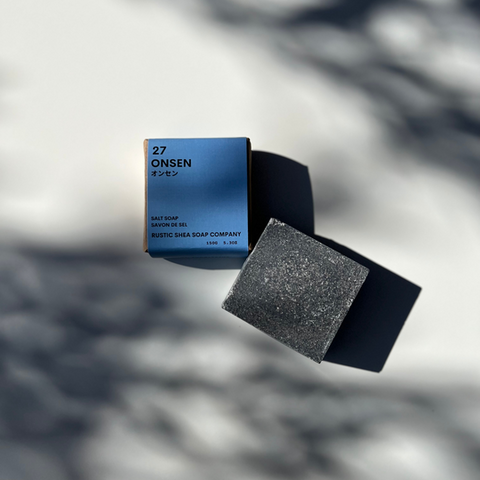 Bar of black soap with a blue box labeled '27 Onsen' on a blurred background