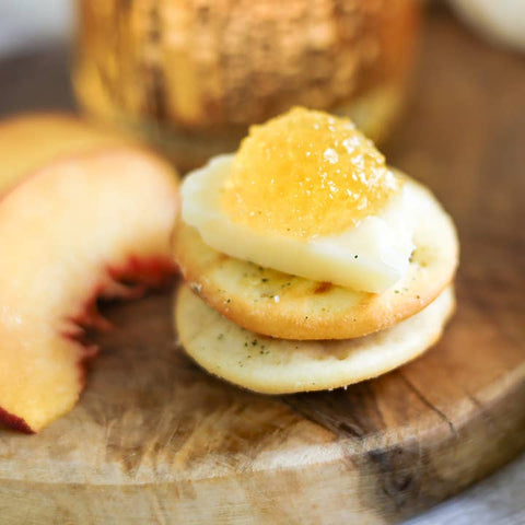 Small dessert with cream and peach slices on a wooden board