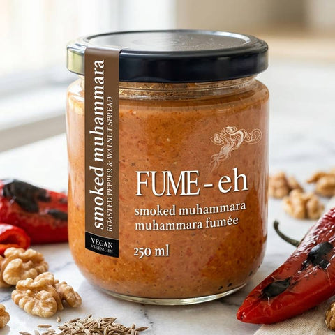 Jar of smoked muhammara with ingredients on a marble surface