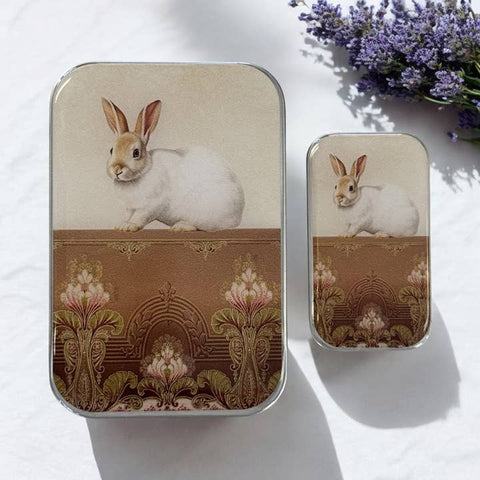 Two tin containers with rabbit illustrations on a white background