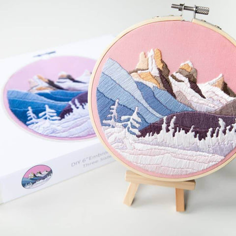Embroidery hoop with mountain landscape design on a pink background