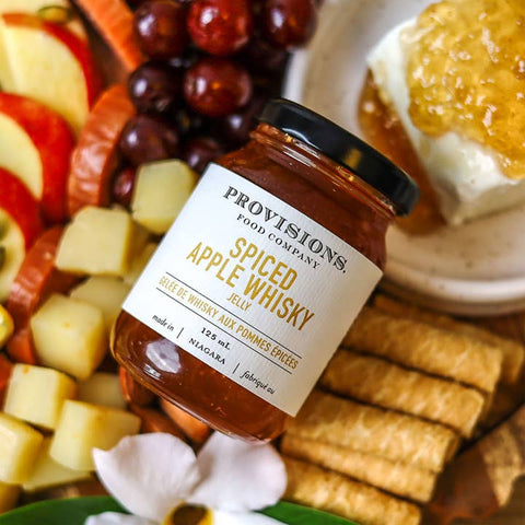 Provisions Food Company Spiced Apple Whisky jelly jar on a platter with fruit and cheese.