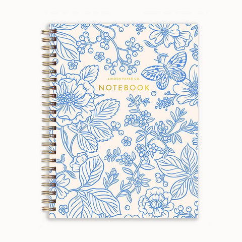 A spiral-bound notebook with a white cover decorated in blue floral and botanical line art, featuring a butterfly motif and gold foil text that reads 'LINDEN PAPER CO. NOTEBOOK'.