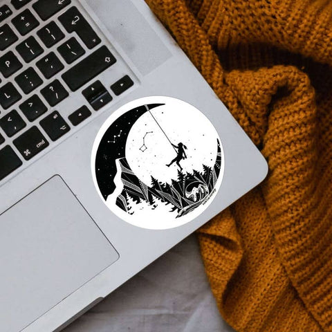 Laptop with a sticker of a silhouette of a person on a mountain and a crescent moon.