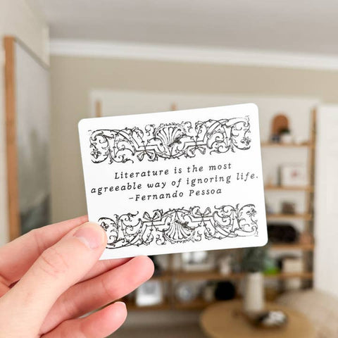 Hand holding a card with a quote by Fernando Pessoa in a room setting