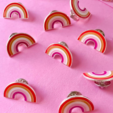 Rainbow-shaped pins on a pink background