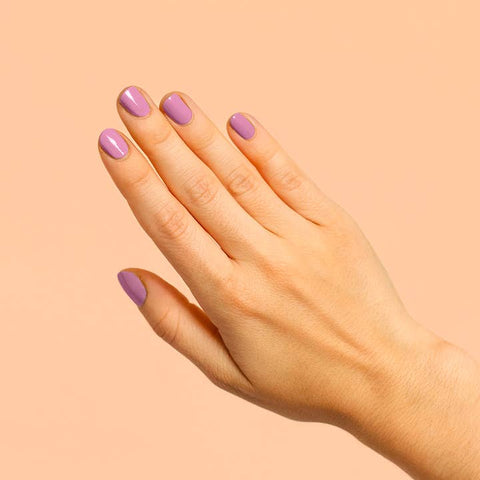 Hand with purple nail polish on a peach background