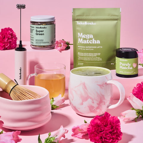 Matcha tea products including a bag, container, and cup on a pink background with flowers.