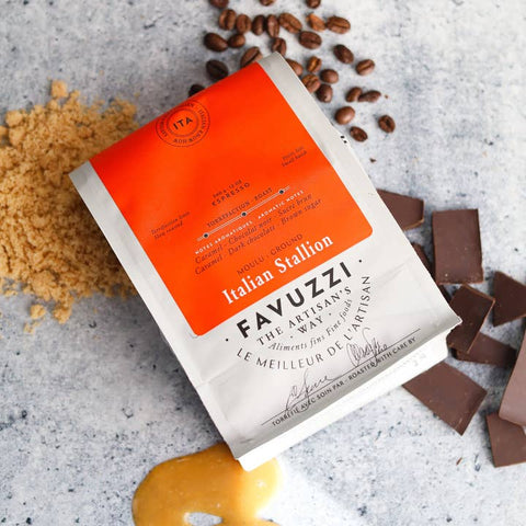 Favuzzi coffee packaging with coffee beans, sugar, and chocolate on a gray surface