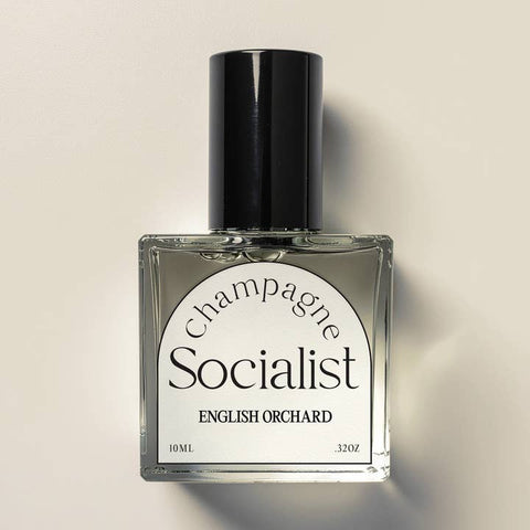 Perfume bottle labeled 'Champagne Socialist English Orchard' on a beige background