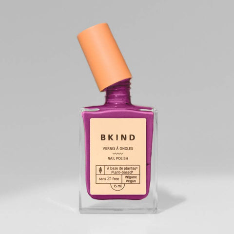 Purple nail polish bottle with orange cap on a gray background