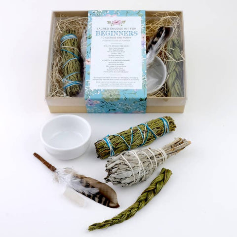 Sage smudge kit with sticks, bowl, feather, and packaging on a white background