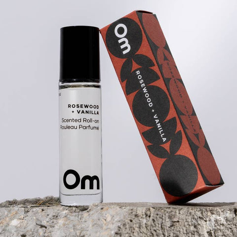 Roll-on perfume bottle and packaging with 'Om' branding on a neutral background