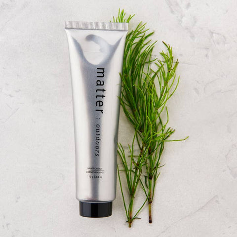 Tube of 'matter outdoors' hand cream with a branch on a textured white background