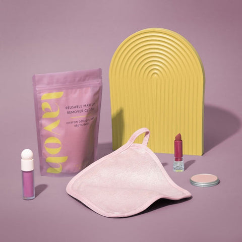 Set of reusable makeup remover products including a pink bag, purple packaging, and a yellow tool on a purple background.
