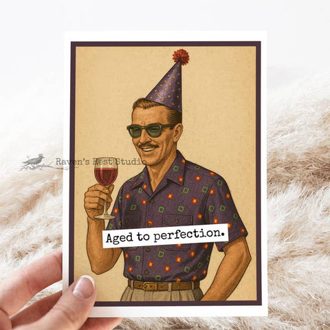 Card with illustration of a man in a party hat holding a glass of wine, text 'Aged to perfection', on a textured surface.