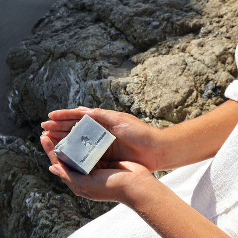 Person holding a bar of soap against a rocky background