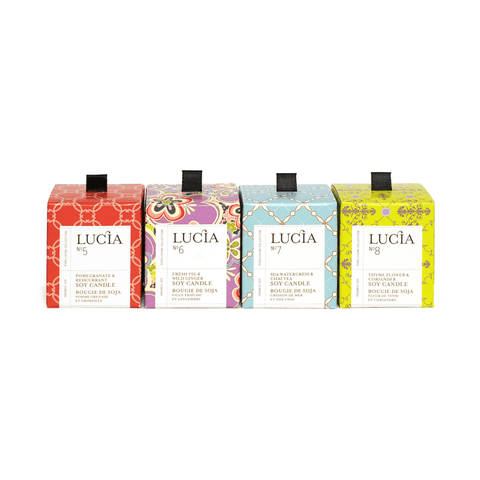 Four Lucia candles in different packaging designs on a white background