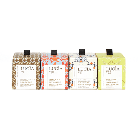 Four Lucia candles in different packaging designs on a white background