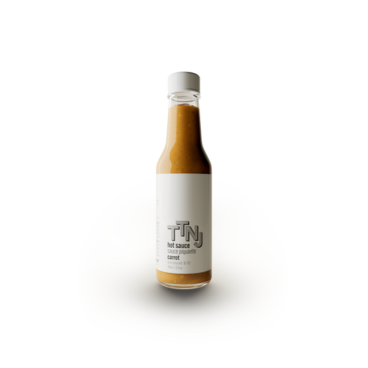 carrot hot sauce by ttnj in glass bottle with white label