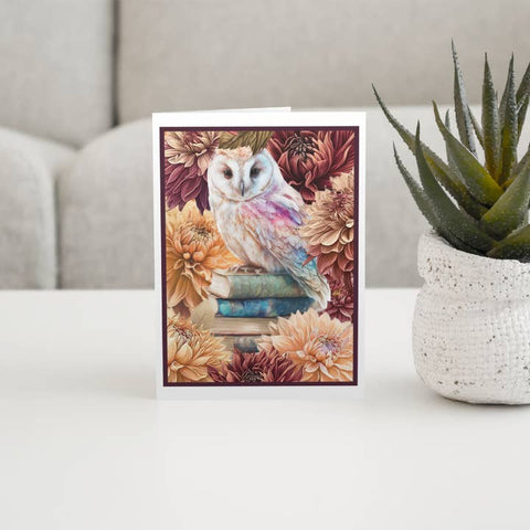 Greeting card with owl design on a table next to a plant