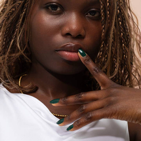 Woman with braided hair and green nail polish touching her lips