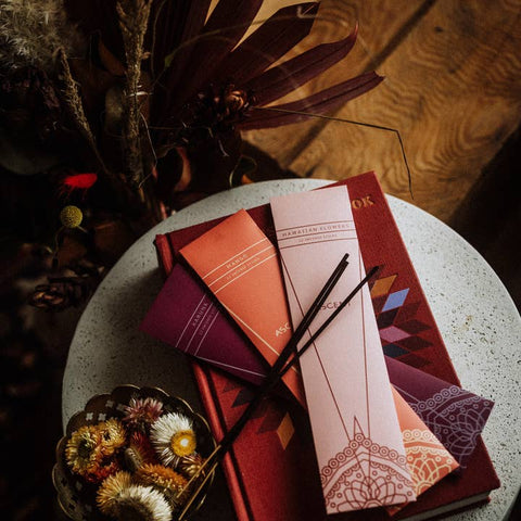 Colorful books with decorative covers on a textured surface with dried plants.