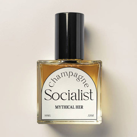 Perfume bottle labeled 'Champagne Socialist' by 'Mythical Her' on a beige background