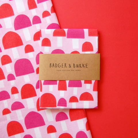 Pink and red patterned tea towels with a 'Badger & Burke' label on a red background
